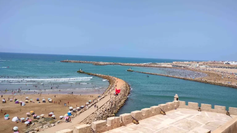 Crowded summer beach in Rabat with swimmers and umbrellas, seen from the Kasbah of the Udayas